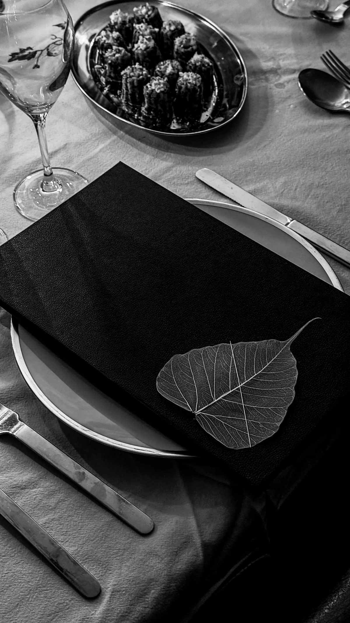 Livret noir orné d’une feuille séchée, posé sur une assiette