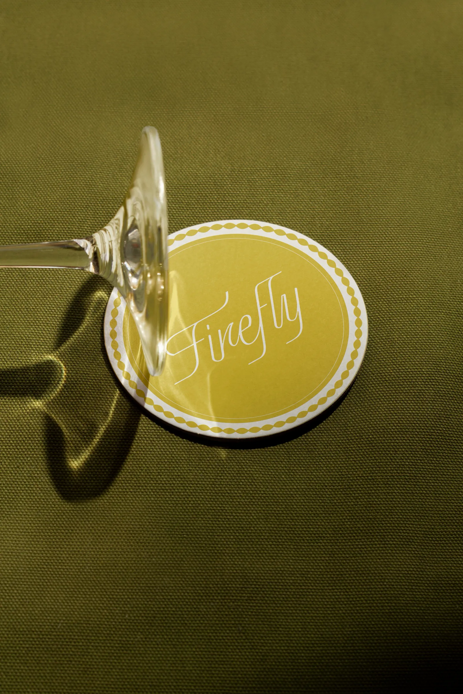 Sous-verre jaune au lettrage Firefly sous un verre à pied