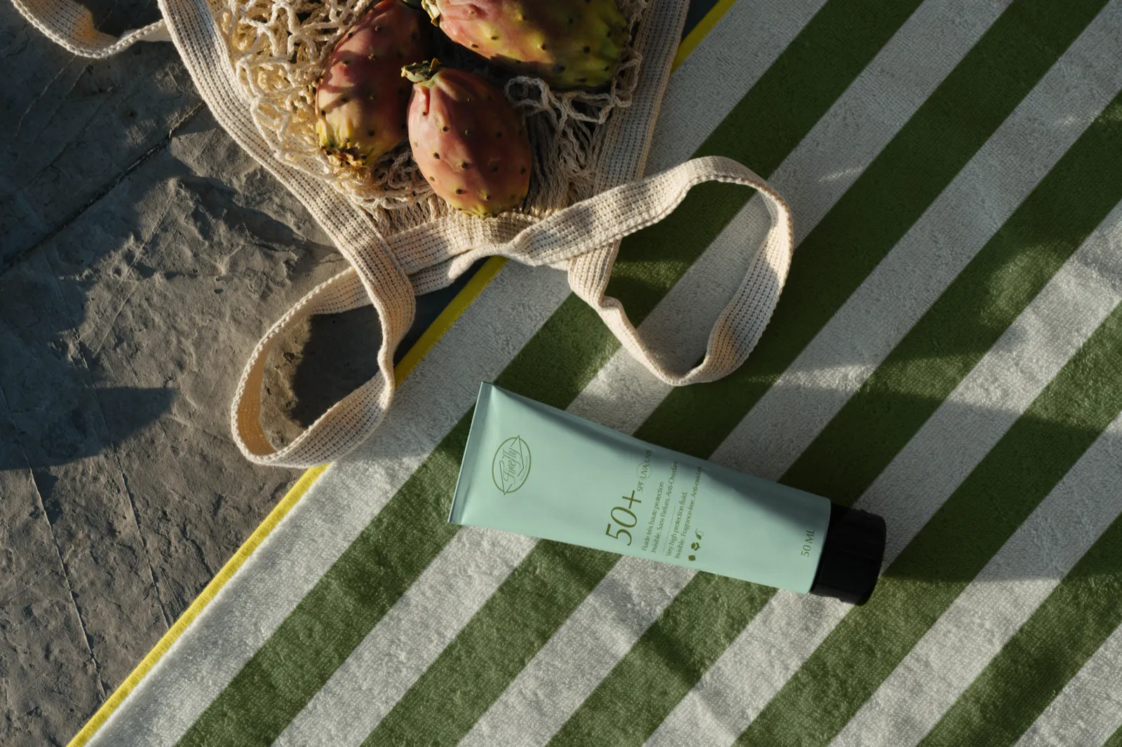 Tube de crème Firefly vert d’eau posé sur un sac en filet